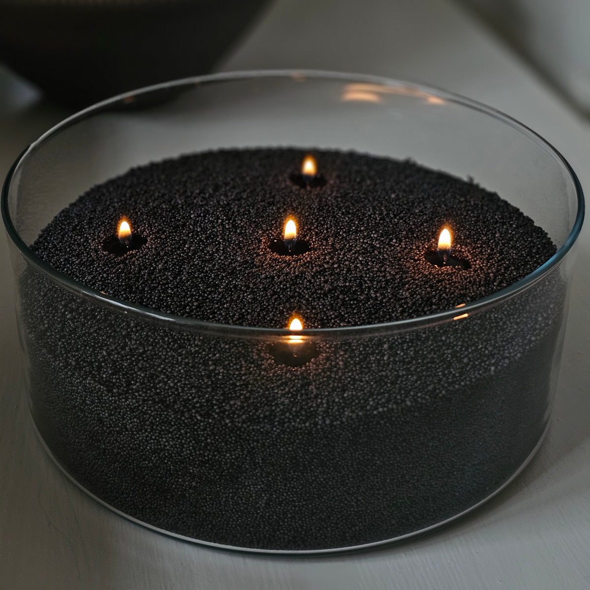 Five-wick black wax pearl candle in a wide clear glass bowl, creating a large statement candle display.