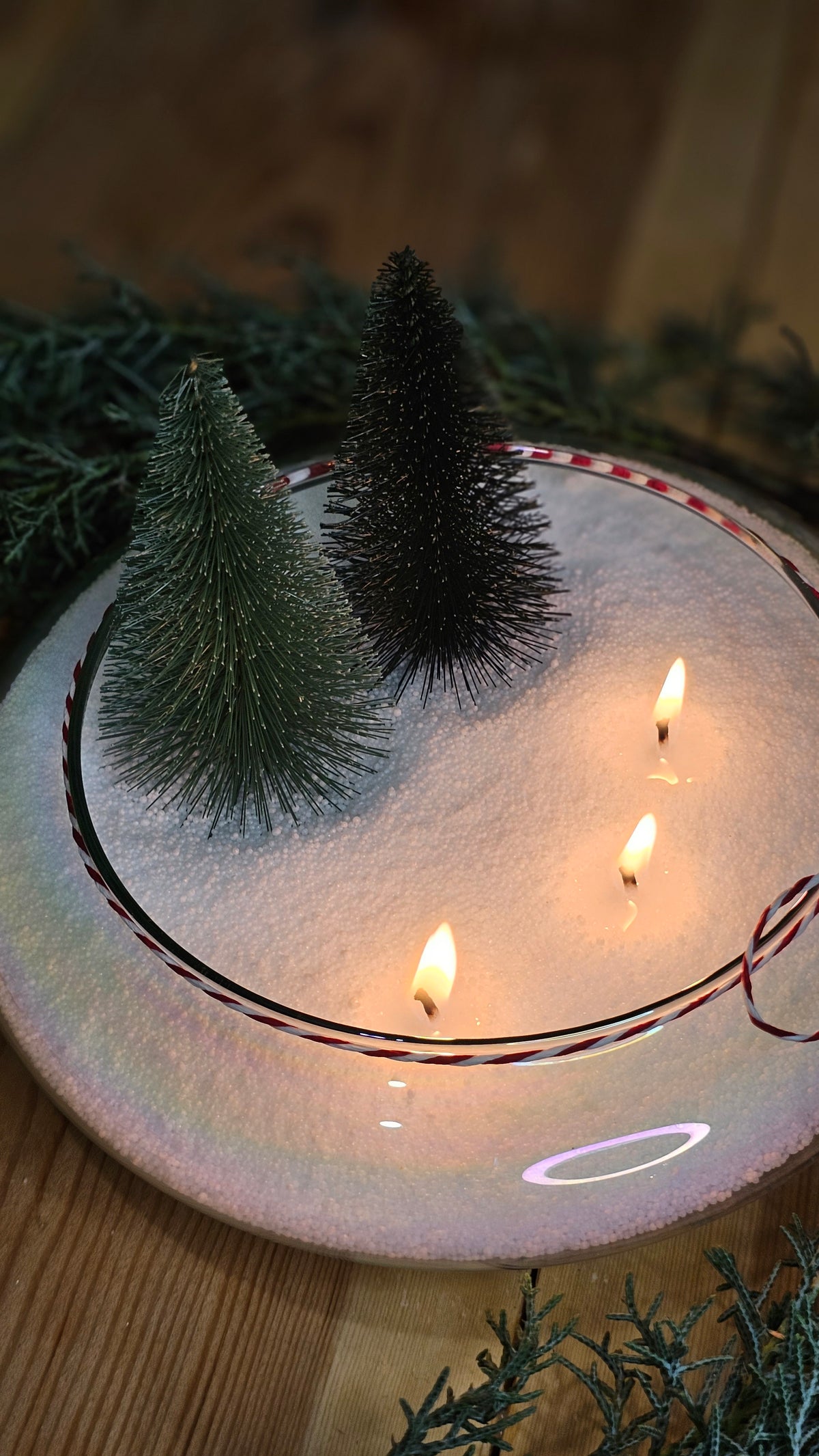 Multi-wick Christmas candle centrepiece in a glass bowl with bottle-brush trees and candy canes.