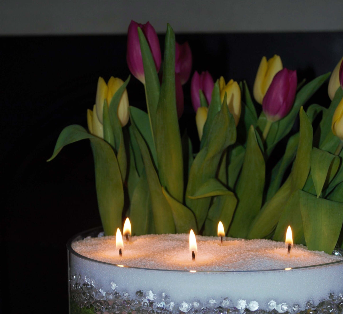 Four-wick floating pearled candle in a crystal-trimmed glass bowl, styled with colourful tulips.