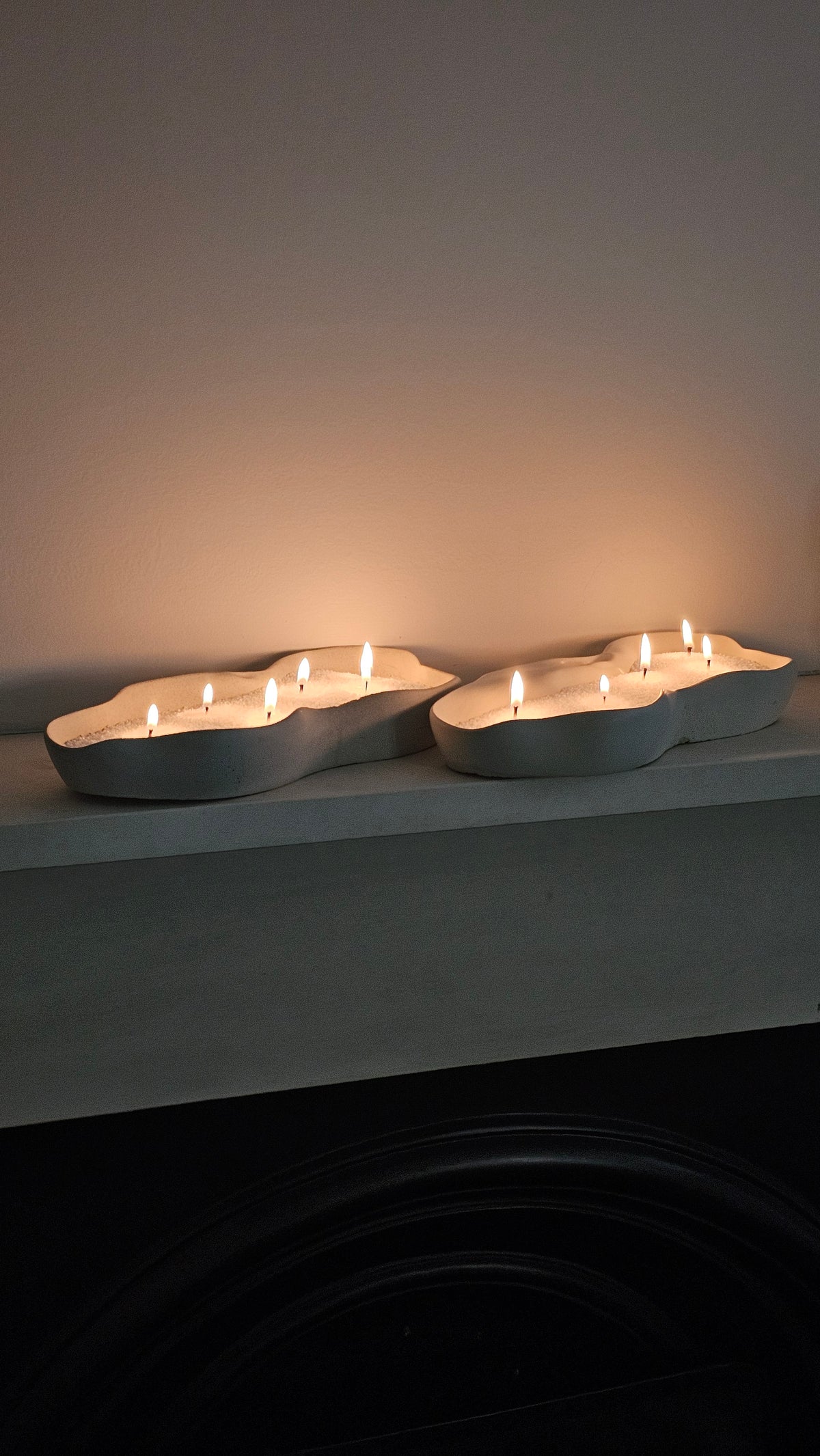 Two sculptural wave candle bowls filled with white wax pearls and multiple wicks for modern home decor.